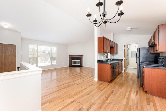 kitchen with dark countertops, open floor plan, light wood-style floors, a chandelier, and lofted ceiling