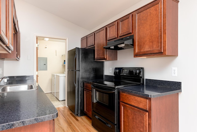 kitchen featuring a sink, vaulted ceiling, under cabinet range hood, washer and dryer, and black appliances