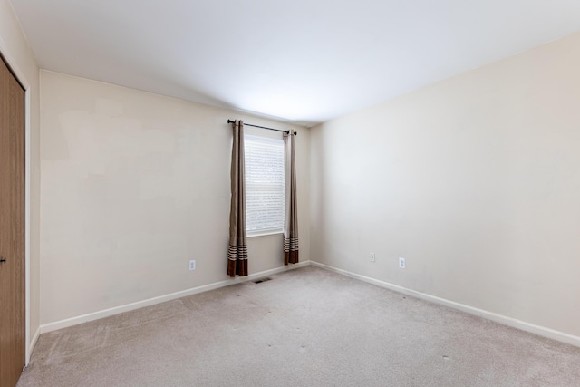 unfurnished room featuring carpet floors, visible vents, and baseboards