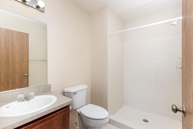 bathroom with vanity, a tile shower, and toilet