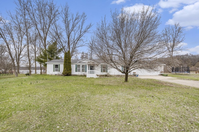 view of front of house with concrete driveway, a front lawn, and a trampoline