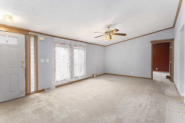 carpeted foyer featuring ceiling fan, baseboards, crown molding, and visible vents