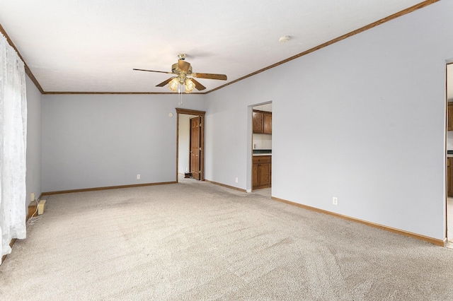 empty room featuring ornamental molding, a ceiling fan, baseboards, and light carpet