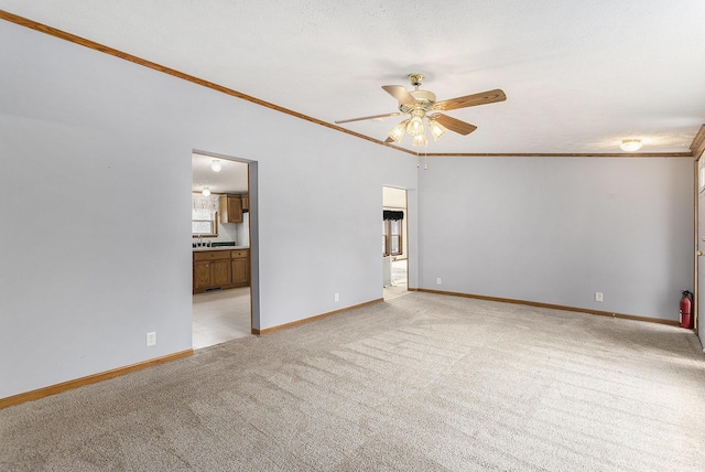 unfurnished room with baseboards, light colored carpet, ceiling fan, and crown molding