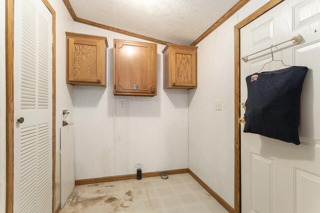 washroom with baseboards, a textured ceiling, ornamental molding, and cabinet space