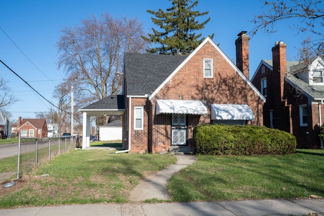 view of front facade featuring brick siding, a shingled roof, a front lawn, and fence