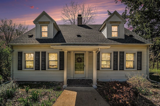 view of front of home with a chimney and roof with shingles