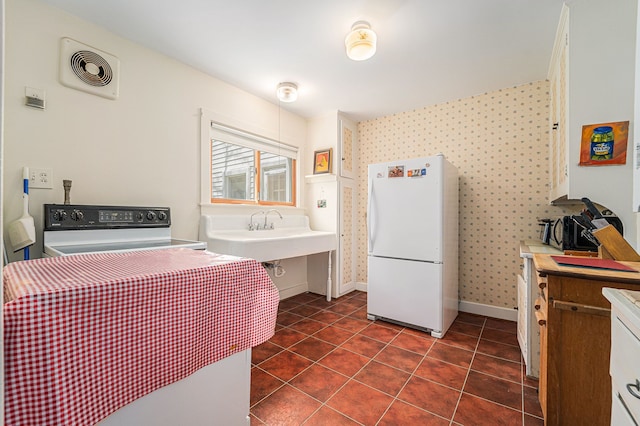 laundry room with wallpapered walls, baseboards, a sink, and dark tile patterned floors