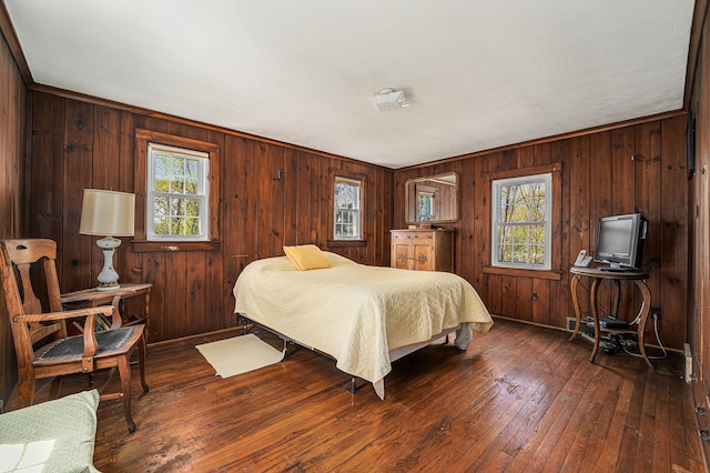 bedroom with wood-type flooring, wood walls, and baseboards