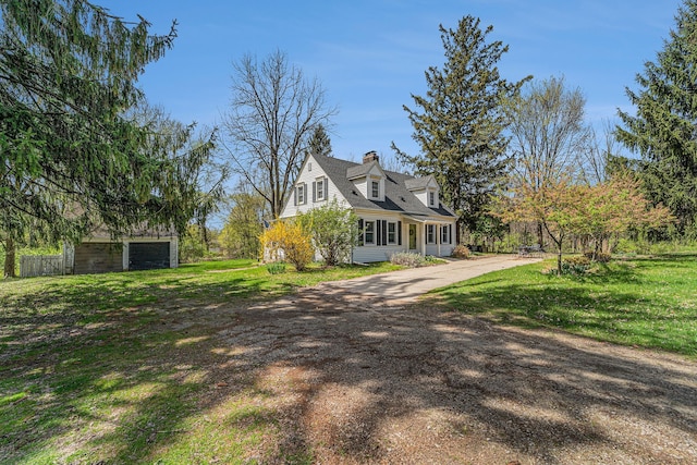 view of home's exterior featuring a chimney, driveway, an outdoor structure, and a yard