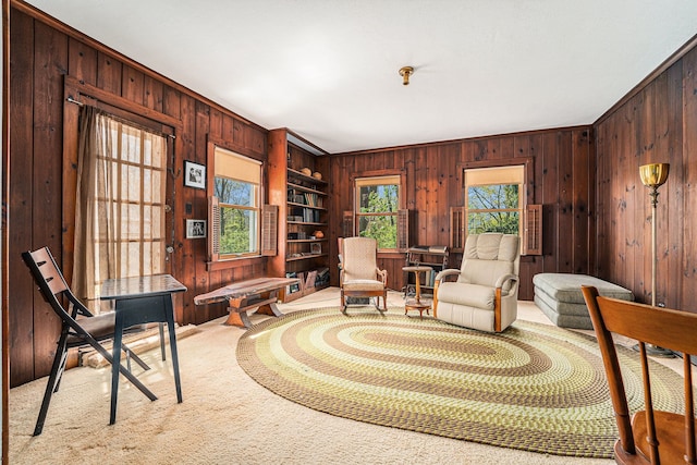 sitting room featuring wood walls, carpet floors, and ornamental molding