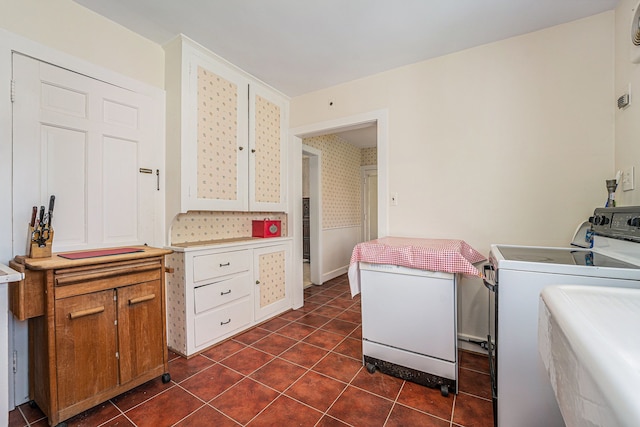 laundry area featuring washing machine and dryer, dark tile patterned flooring, and wallpapered walls