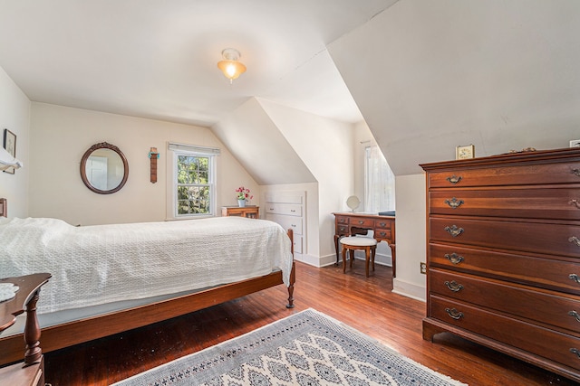 bedroom with wood finished floors, lofted ceiling, and baseboards