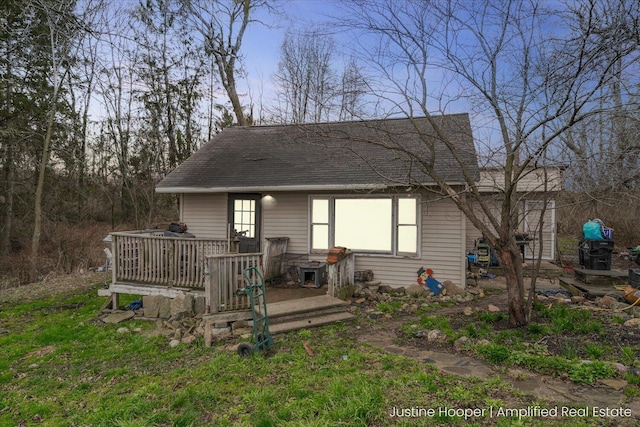 exterior space with a deck and a shingled roof
