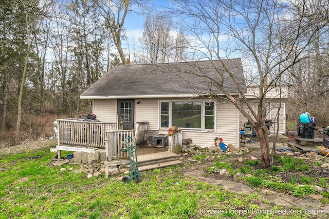 view of front facade featuring roof with shingles and a deck
