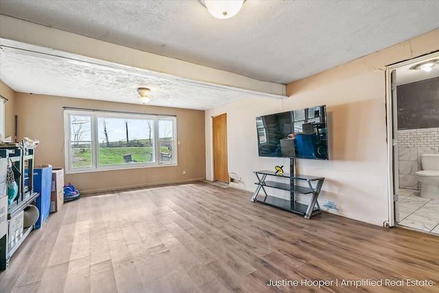 interior space with beam ceiling, wood finished floors, and a textured ceiling