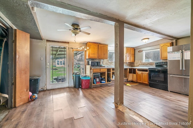 kitchen with ceiling fan, appliances with stainless steel finishes, beam ceiling, and light wood-style flooring