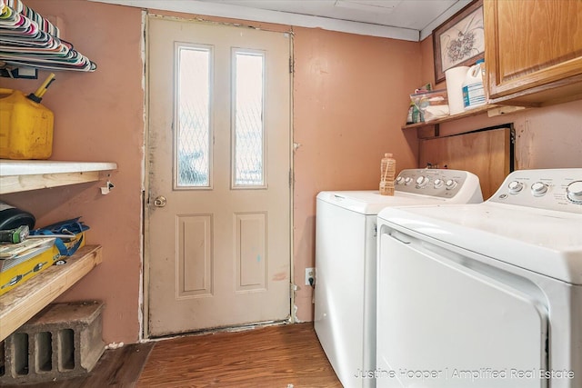 laundry area featuring washing machine and dryer, wood finished floors, and cabinet space