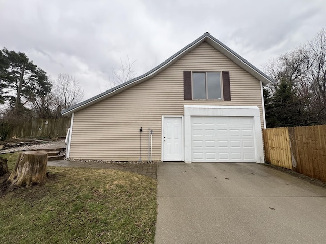 view of side of home featuring an attached garage, driveway, and fence