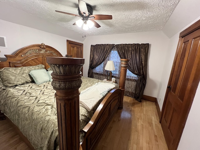 bedroom featuring light wood-style floors, a textured ceiling, baseboards, and ceiling fan