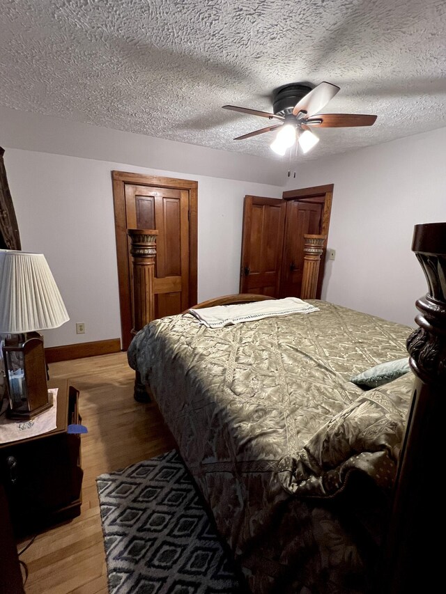 bedroom with light wood-type flooring, a textured ceiling, baseboards, and ceiling fan