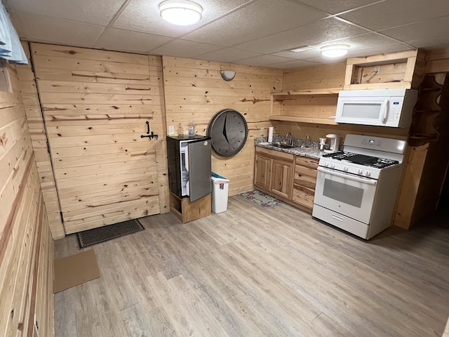kitchen with light wood finished floors, white appliances, visible vents, and a drop ceiling