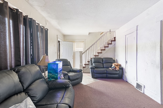 carpeted living area with stairs and a textured ceiling