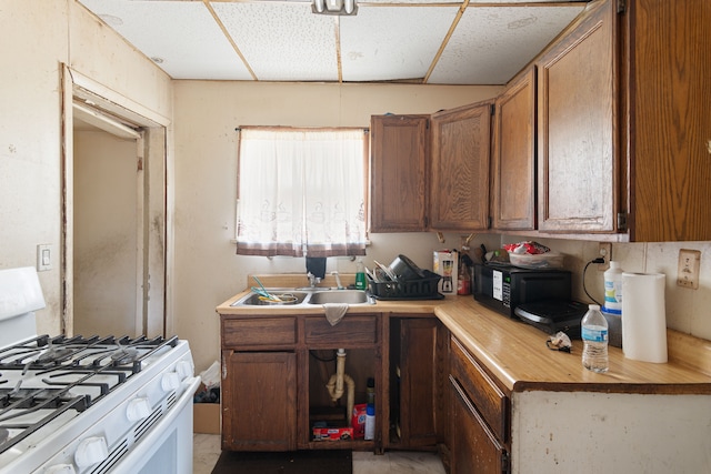 kitchen featuring gas range gas stove, a sink, wood counters, black microwave, and brown cabinetry