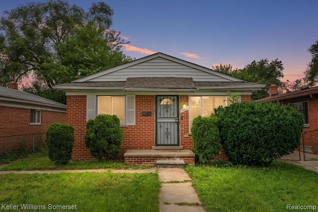 bungalow-style home featuring a lawn and brick siding