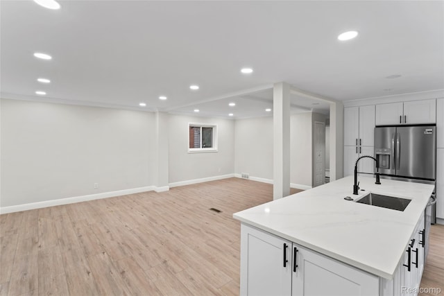 3761 Campbell St, Dearborn, MI 48124 - kitchen with light wood finished floors, a kitchen island with sink, recessed lighting, white cabinets, and stainless steel refrigerator with ice dispenser