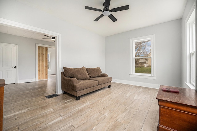 living area with light wood finished floors, a ceiling fan, baseboards, and visible vents