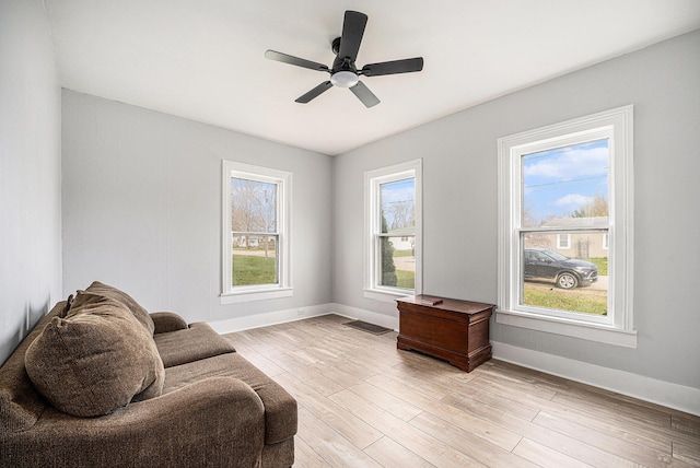 sitting room with light wood-type flooring, visible vents, baseboards, and ceiling fan