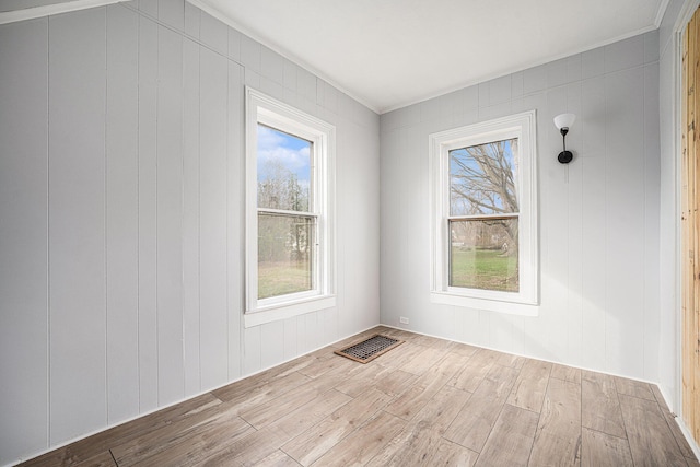 unfurnished room featuring visible vents, plenty of natural light, wood finished floors, and crown molding