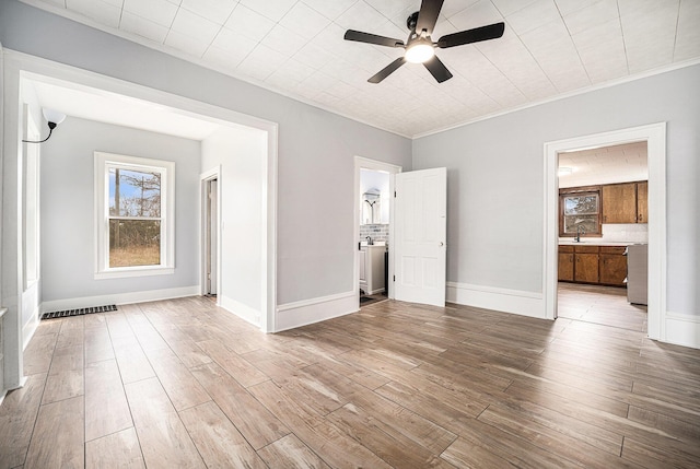 unfurnished bedroom featuring wood finished floors, visible vents, ornamental molding, and a sink