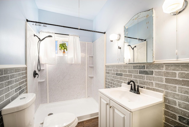 bathroom with vanity, toilet, a stall shower, and wainscoting