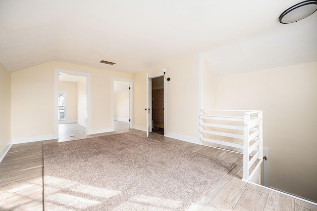additional living space featuring visible vents, baseboards, vaulted ceiling, and wood finished floors