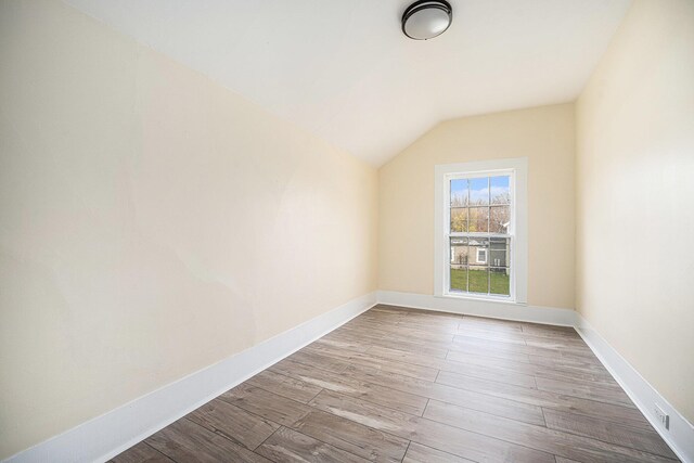 additional living space with vaulted ceiling, wood finished floors, and baseboards