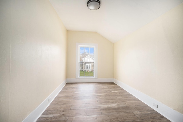 additional living space with lofted ceiling, wood finished floors, and baseboards