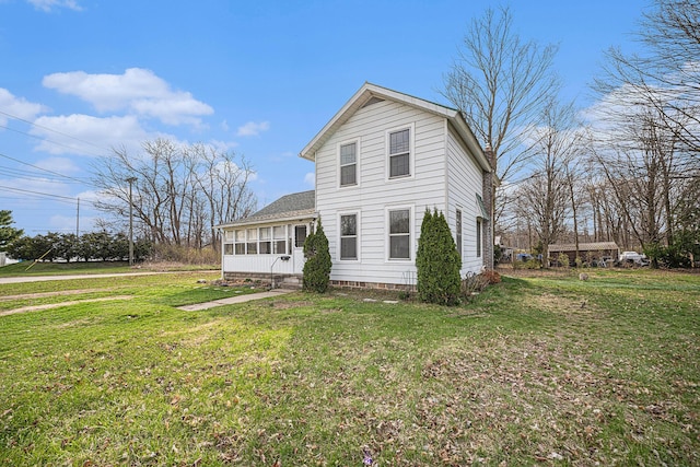 view of front of home with a sunroom, roof with shingles, and a front yard