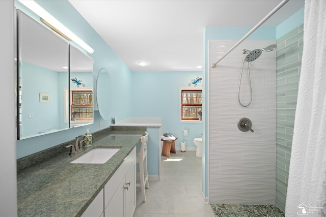 bathroom featuring tiled shower, vanity, tile patterned flooring, and toilet