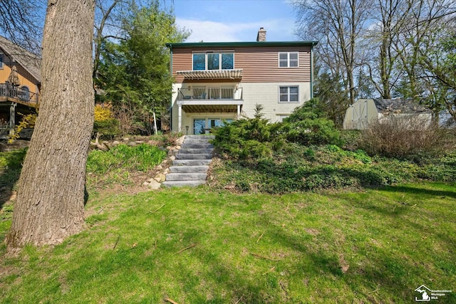 rear view of house with a chimney, stairway, a balcony, and a lawn