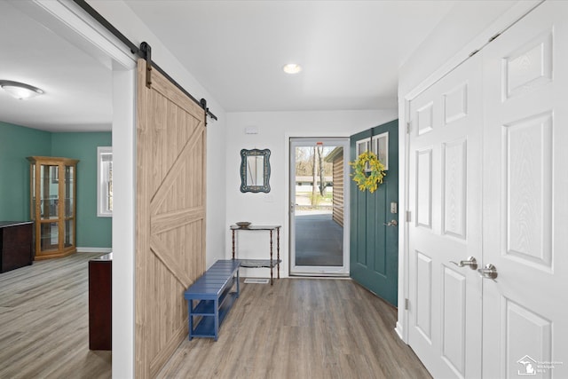 entrance foyer featuring a barn door, baseboards, wood finished floors, and recessed lighting