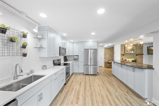 kitchen with white cabinets, stainless steel appliances, a sink, light wood-style floors, and open shelves