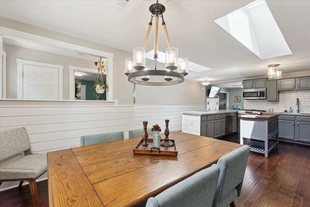 2510 Ruth Dr, Fenton, MI 48430 - dining space with a skylight, a chandelier, dark wood-style flooring, and a wainscoted wall
