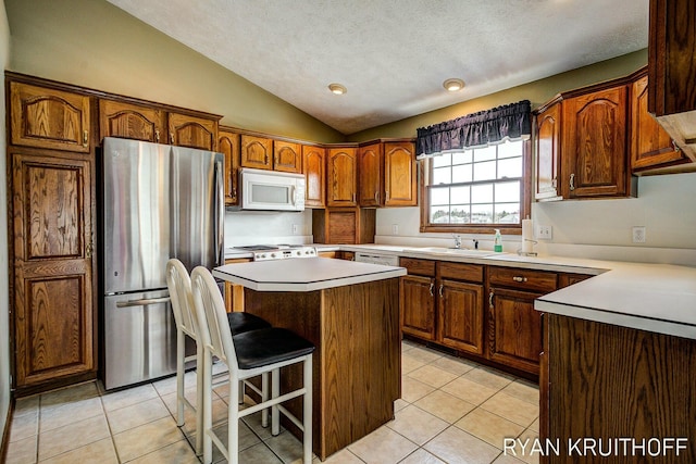 3076 Regency Pkwy, Zeeland, MI 49464 - kitchen with light tile patterned flooring, lofted ceiling, a center island, and white appliances