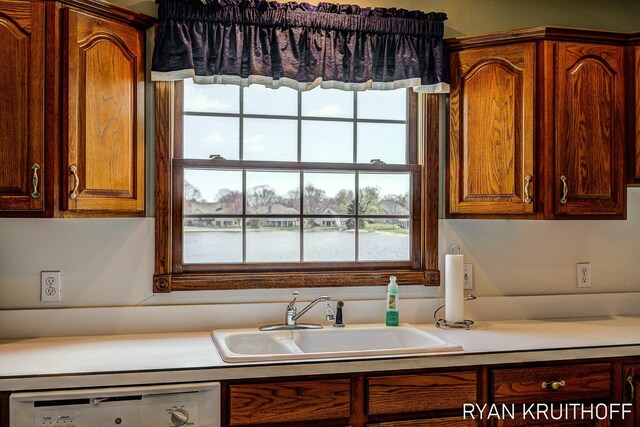 3076 Regency Pkwy, Zeeland, MI 49464 - kitchen with brown cabinetry, dishwasher, light countertops, and a sink