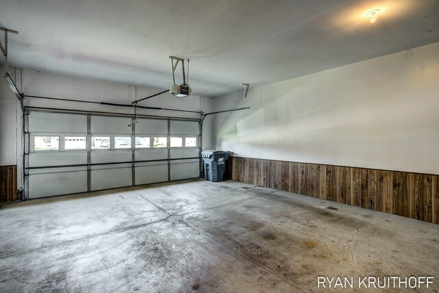 3076 Regency Pkwy, Zeeland, MI 49464 - garage featuring a wainscoted wall, wood walls, and a garage door opener