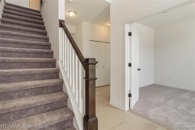 stairs featuring baseboards, wood finished floors, and carpet floors