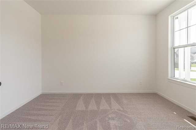 carpeted spare room featuring visible vents and baseboards