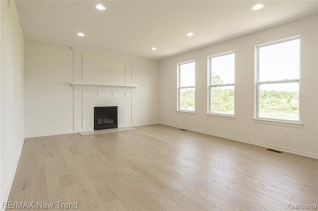 unfurnished living room with light wood-style flooring, baseboards, visible vents, recessed lighting, and a brick fireplace